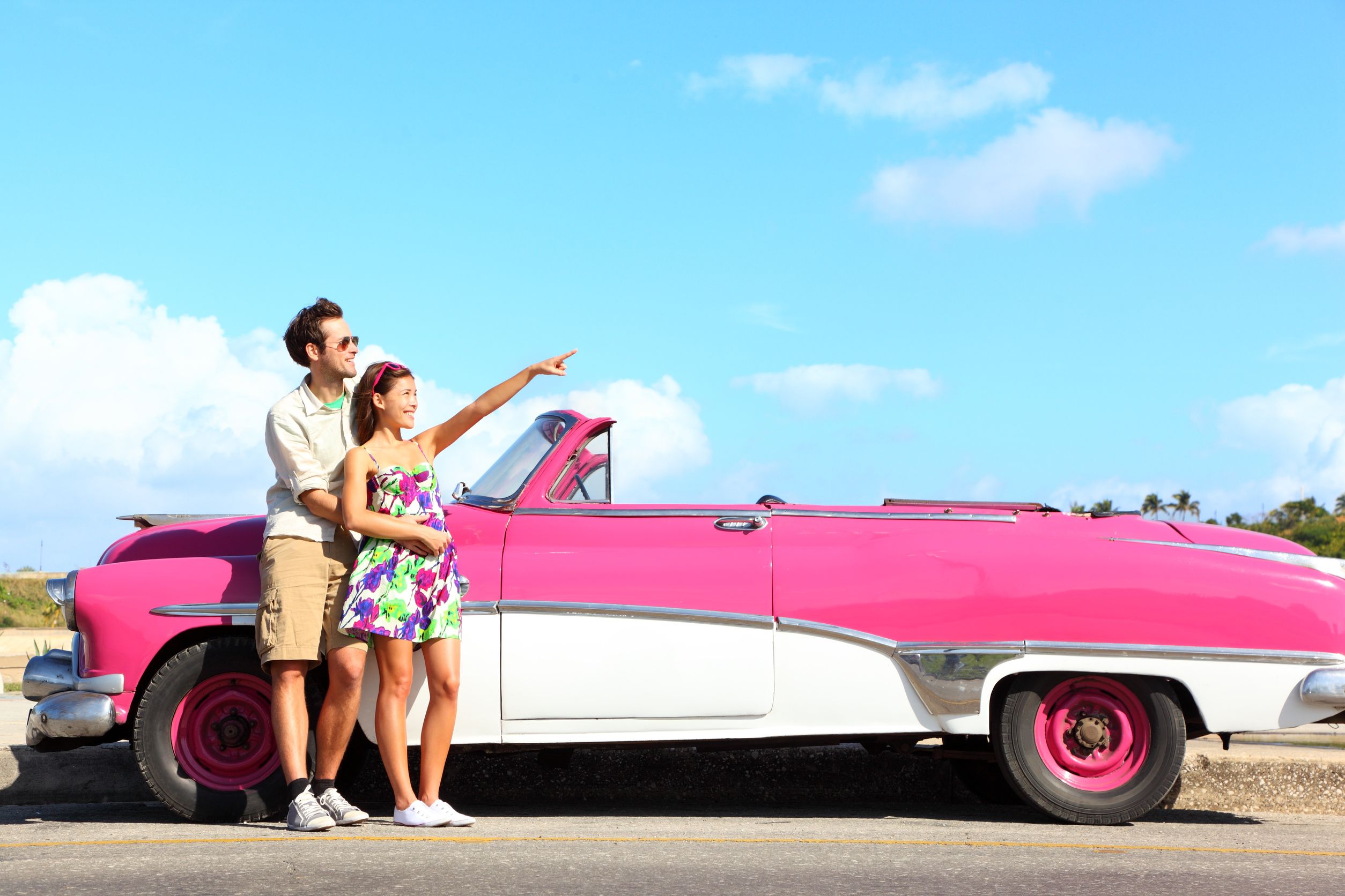 vintage-car-couple-pointing-looking-standing-by-pink-retro-vintage-car-smiling-happy-young-couple-on-summer-road-trip-car-holiday-in-Havana-Cuba